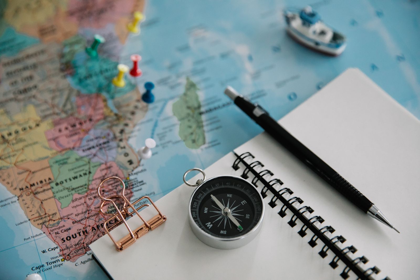 Flat lay of a map, compass, and notebook for trip planning